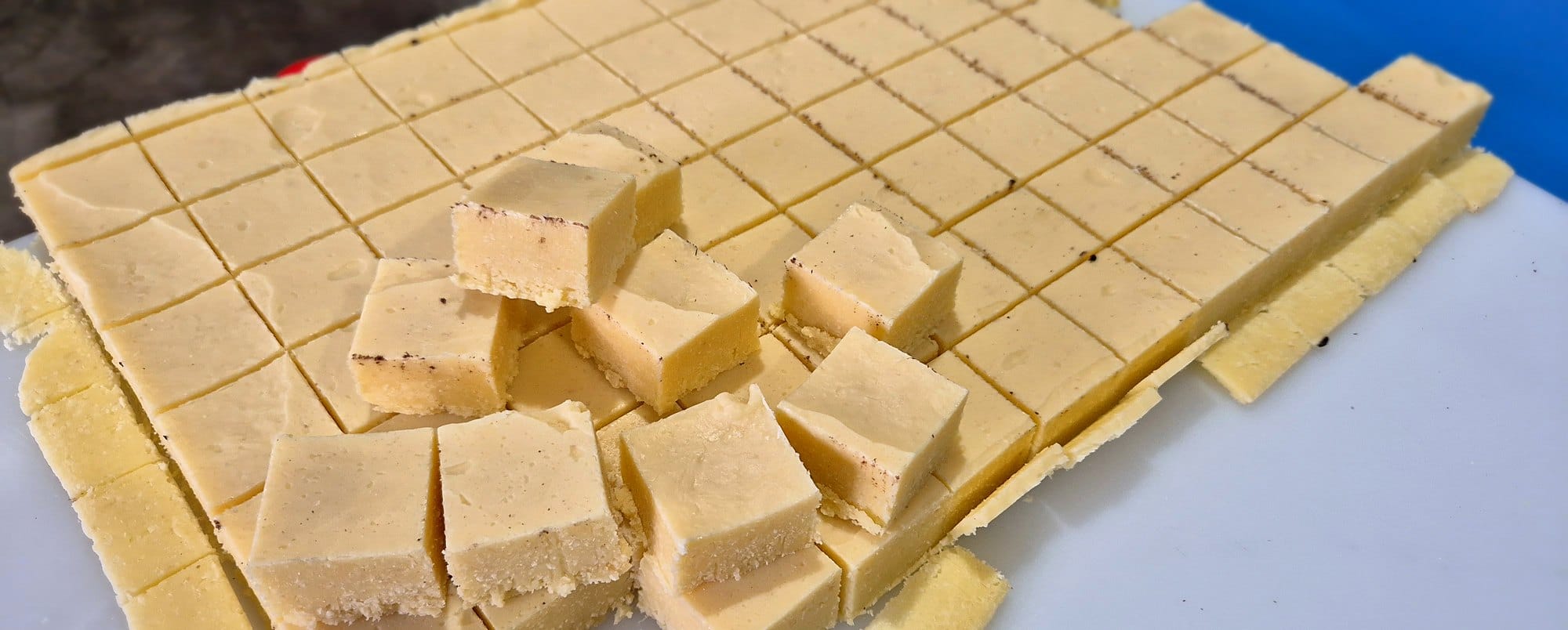Barfi cut into even squares, with a few pieces lifted out